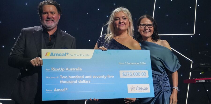 Nicolle Edwards, CEO of RizeUp Australia holding an oversized cheque on stage at the Gala